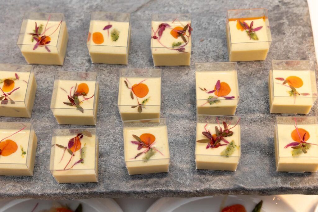 Delicious white chocolate squares decorated with colorful edible flowers and herbs, arranged on a ru.