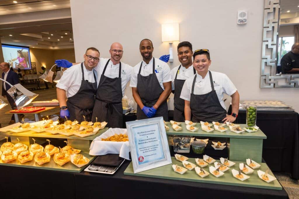 Diverse culinary team at Quantum House preparing gourmet dishes for event.