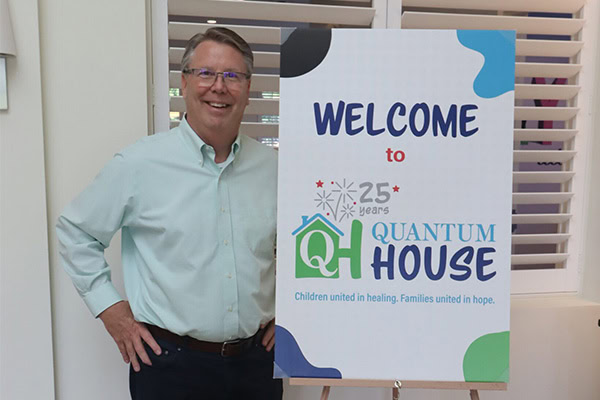 Greg Quattlebaum next to a Quantum House Sign